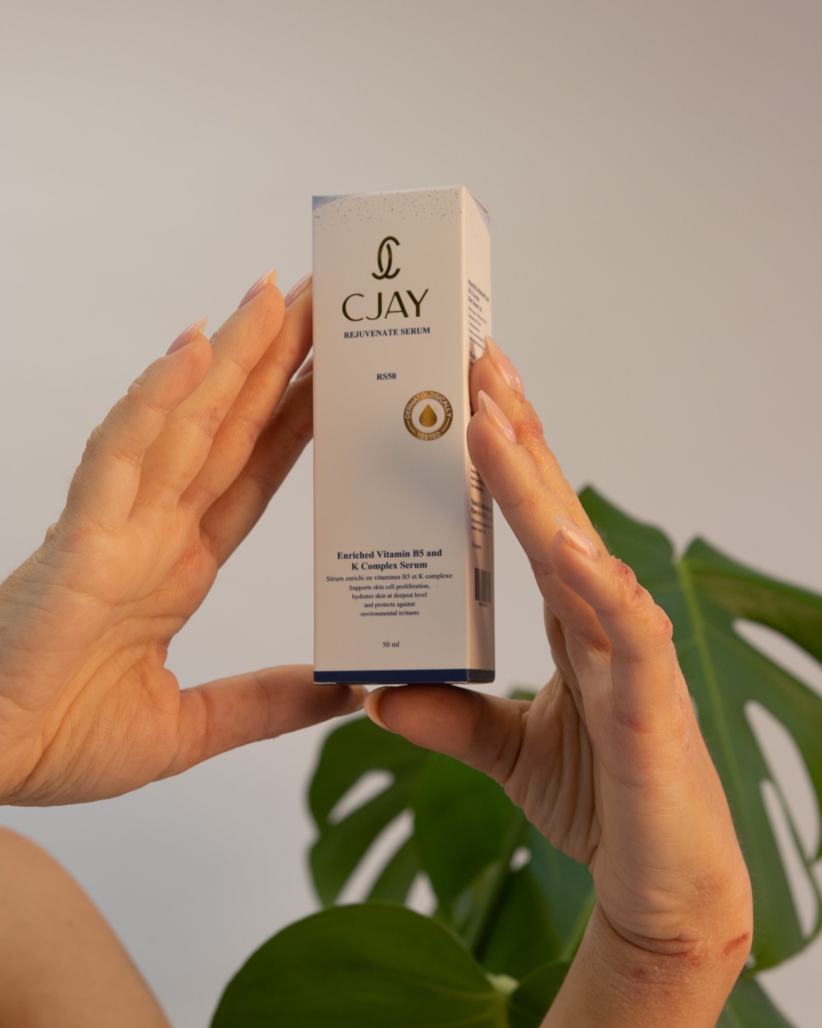 CJAY skincare serum box held by hands with a plant in the background